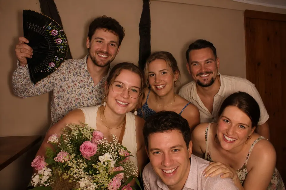 Freundesgruppe mit Blumenstrauß und Fächer posiert fröhlich