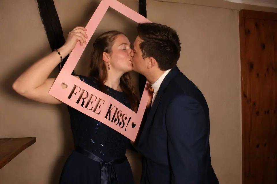 Paar küsst sich hinter einem rosa „Free Kiss“-Rahmen